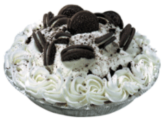 A pie topped with whipped cream and chocolate sandwich cookie halves is displayed on a silver dish. Crumbled cookies sprinkle over the whipped cream, enhancing a dessert table setting.